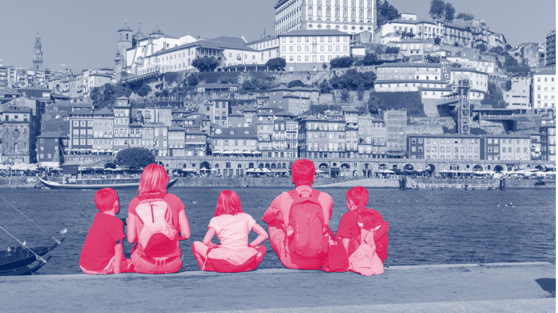 Family sitting on the wall of a port overlooking the city of Porto in Portugal